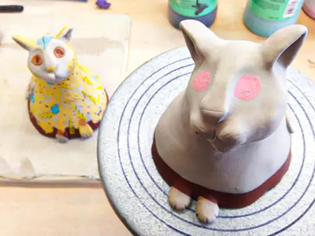 The cats getting decorated. First comes the white slip, then the underglazes are applied.